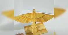 a golden bird sculpture sitting on top of a wooden table next to a white box