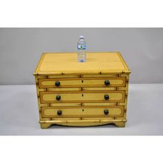 a wooden chest with two drawers and a bottle of water sitting on top of it