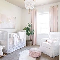 a baby's room with a white crib, pink curtains, and a chandelier