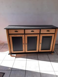 a wooden cabinet sitting on top of a tiled floor