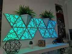 two planters are lit up on the wall next to each other with plants in them