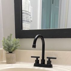 a bathroom sink with a black faucet and mirror