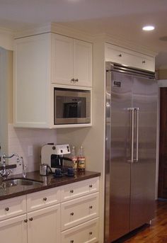 a kitchen with white cabinets and stainless steel refrigerator freezer next to wooden flooring