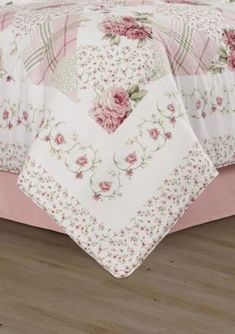 a bed covered in pink and white bedspread with flowers on the comforter