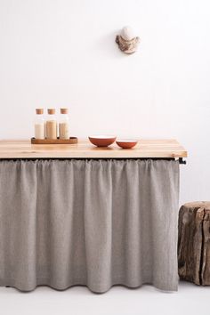 a wooden table topped with bowls next to a white wall