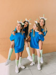 three girls in blue dresses and green socks posing for the camera with their arms around each other