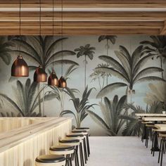 a restaurant with palm trees on the wall and bar stools in front of it