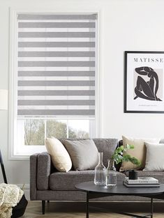 a living room filled with furniture and a window covered in roman blind shades on the windowsill