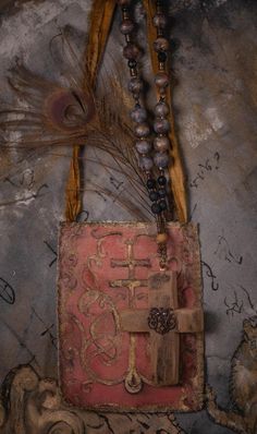 a cross and beads hanging from a bag on a wall next to a tree branch