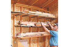 a man in blue shirt working on wooden shelves