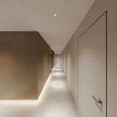 a long hallway with white walls and lights on either side, leading to another room