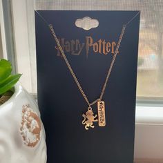 a harry potter necklace and bookmark on a table next to a potted plant