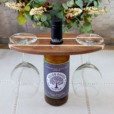 a bottle of wine sitting on top of a wooden table with two glasses underneath it