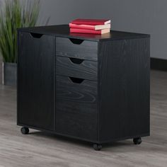 a black wooden cabinet with three drawers and a red book on it's top