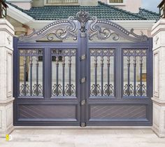 a large blue gate with intricate iron work on it's sides in front of a house