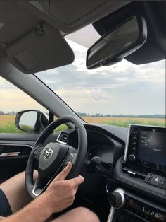 a man driving a car on the road with his hands on the steering wheel and dashboard