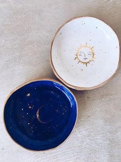 two blue and white bowls with the sun painted on them sitting on a wooden surface