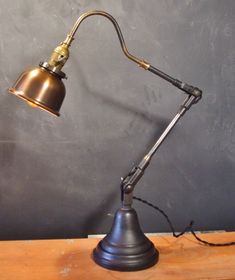 a desk lamp sitting on top of a wooden table next to a blackboard wall