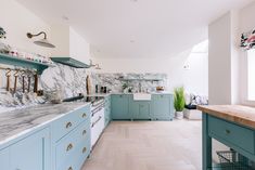 a kitchen with blue cabinets and marble counter tops