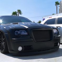 the front end of a black car parked in a parking lot