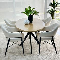 a round table with six chairs and a potted plant on it in front of a window