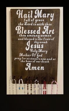 a wooden sign with beads hanging from it's sides and the words, hail mary