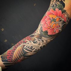 an arm with a dragon and flower tattoo on it