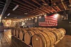 barrels are lined up in the middle of a room with an american flag hanging on the wall