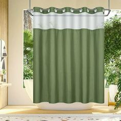 a green and white shower curtain in a bathroom with plants on the window sill