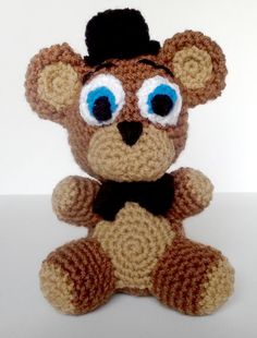 a crocheted teddy bear with blue eyes and a hat on it's head