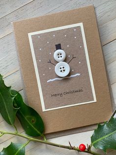 a christmas card with a snowman on it next to holly leaves and a red berry