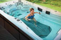 a woman in a large hot tub with a hose