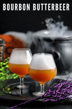 two glasses filled with liquid sitting on top of a metal tray next to halloween decorations