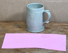 a mug and pink paper on a wooden table