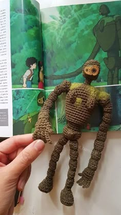 someone is holding up a crocheted toy in front of an open children's book