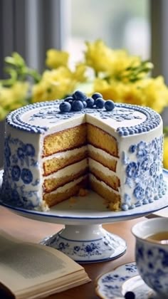 a blue and white cake sitting on top of a table next to a cup of coffee