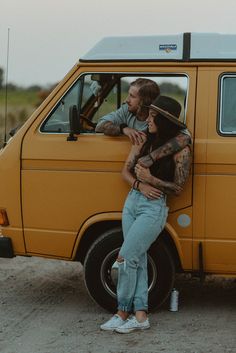 a man and woman standing in front of a van with their arms around each other