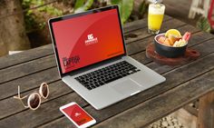 an open laptop computer sitting on top of a wooden table next to a bowl of fruit