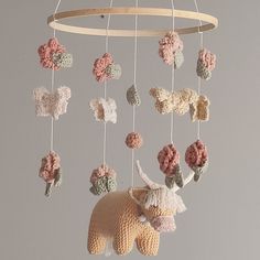 a crocheted animal mobile hanging from a circular wooden frame with flowers on it