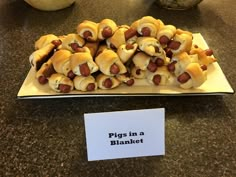 a plate full of pigs in a blanket on a table with a sign that says pigs in a blanket