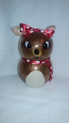 a brown and white teddy bear with a red bow on it's head sitting in front of a white background