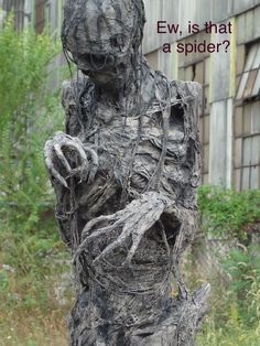 a sculpture is shown in front of a building with vines growing out of it's body