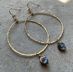 Hammered brass hoop earrings with shell beads. These are approximately 3 inches in length by 1 1/2 inches in width. They are perfect for the summer. Bohemian Hammered Hoop Earrings, Handmade Shell Bohemian Hoop Earrings, Artisan Brass Hoop Earrings, Handmade Shell-shaped Hoop Earrings For Summer, Handmade Gold Shell-shaped Hoop Earrings, Brass Hoop Earrings, Brass Hoops, Shell Beads, Jewelry Earrings Hoops