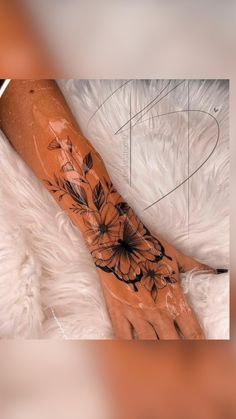 a woman's arm with flowers on it and a black ink design in the middle