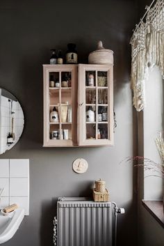 a bathroom with a radiator, sink and cabinet next to a mirror on the wall