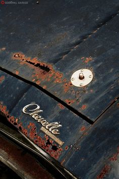 an old car with rusted paint and the word cadillac on it's hood