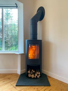 a wood burning stove in the corner of a room next to a window with no curtains