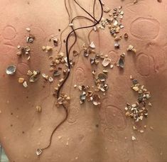 the back of a woman's body with shells and other things on her stomach