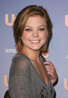 a woman with short hair is smiling at the camera while holding an umbrella in her hand