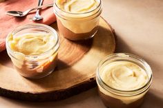 three jars filled with food sitting on top of a wooden tray next to spoons